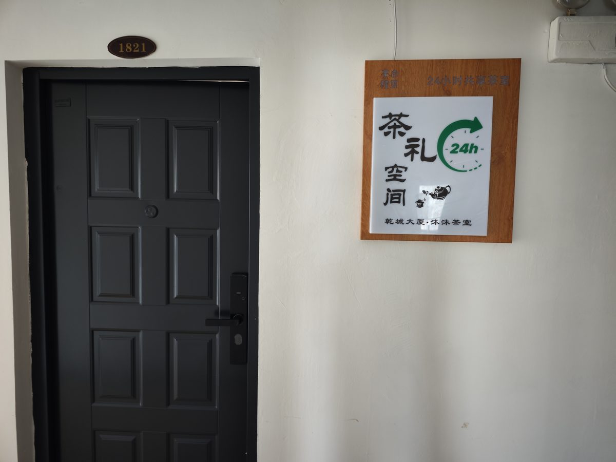 茶礼空间生活馆乾城大厦店门口，黑色大门配木质标识牌