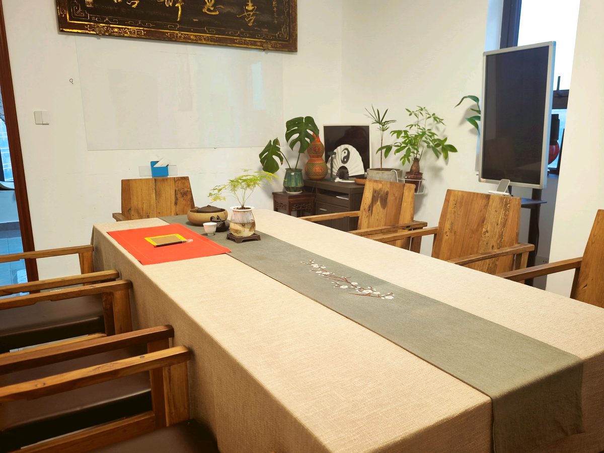 茶礼空间生活馆洋湖天街店店内，长茶桌铺米色桌布与刺绣桌旗，配木质圈椅与绿植